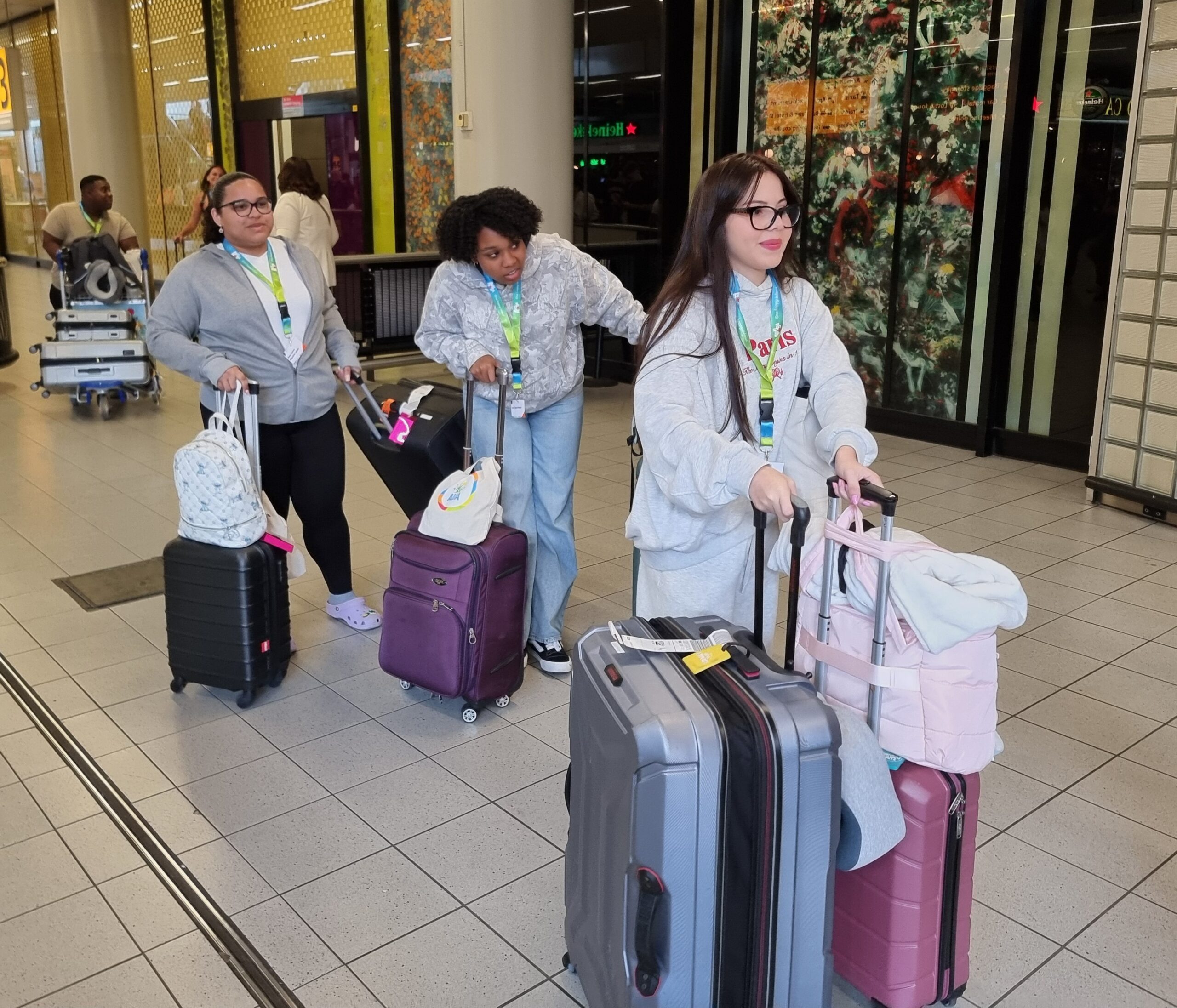 Group of travelers with rolling luggage walking through an airport terminal.