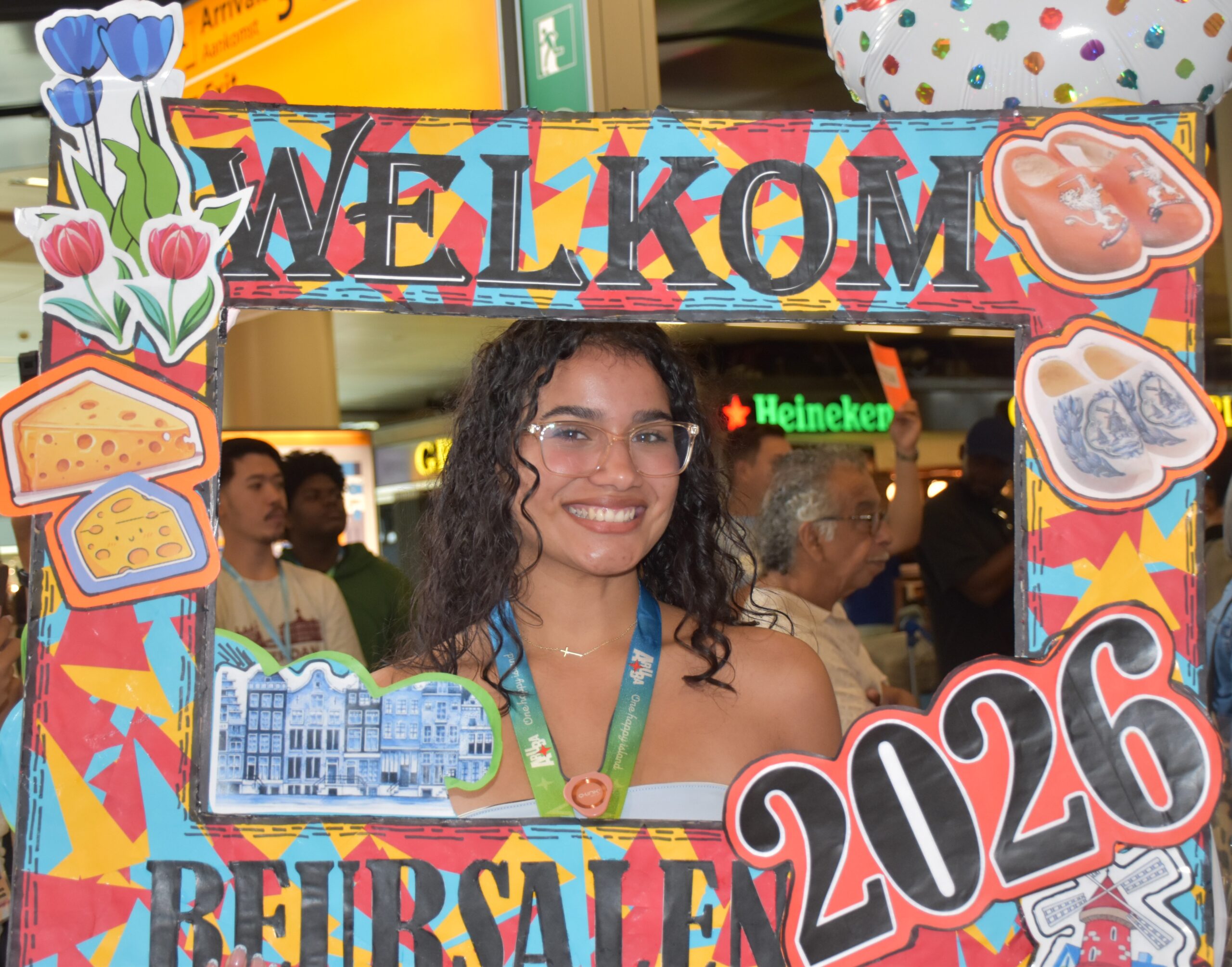 Smiling woman peering through a bright, cartoon-themed photo booth frame decorated with food illustrations.